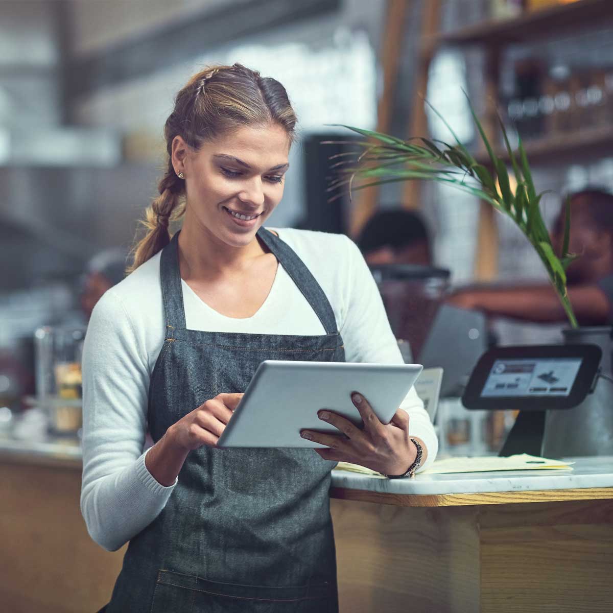 A woman smiling as she uses an electronic tablet.